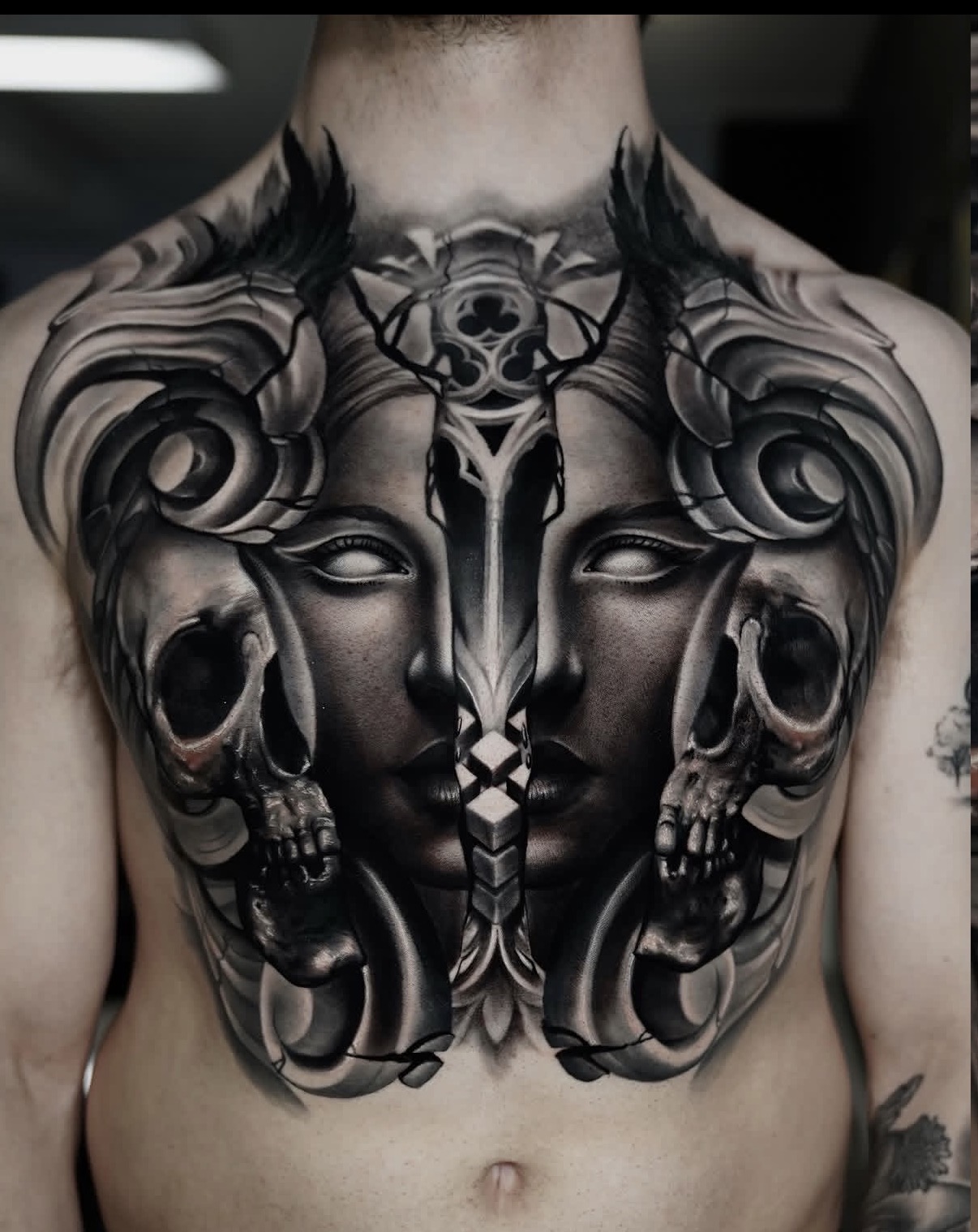 Full-back black-and-grey surreal tattoo with faces and skull