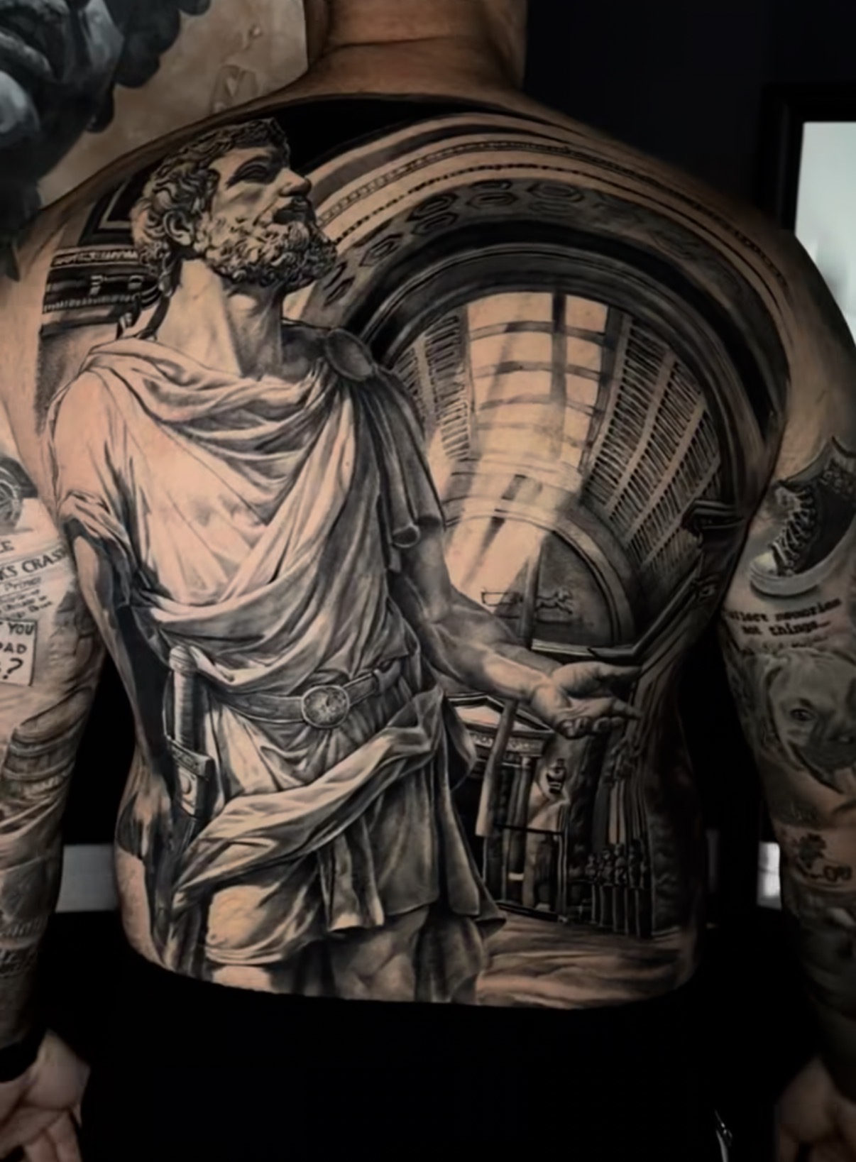 Full-chest black-and-grey realism tattoo with faces and sacred geometry
